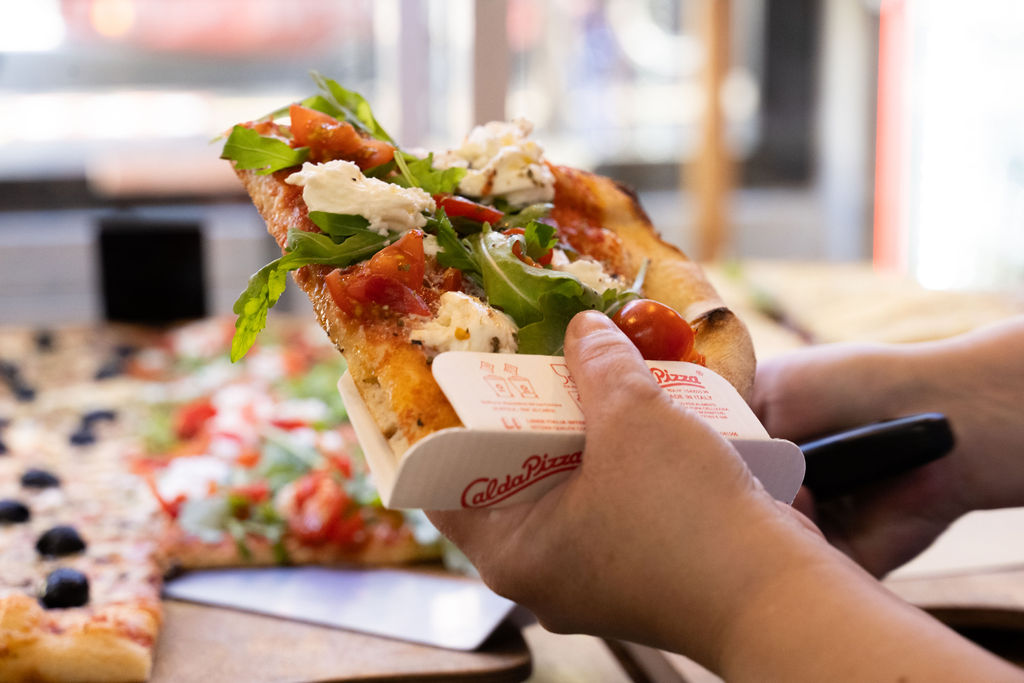 photo de main en train d'emballer une tranche de pizza © eva creative media